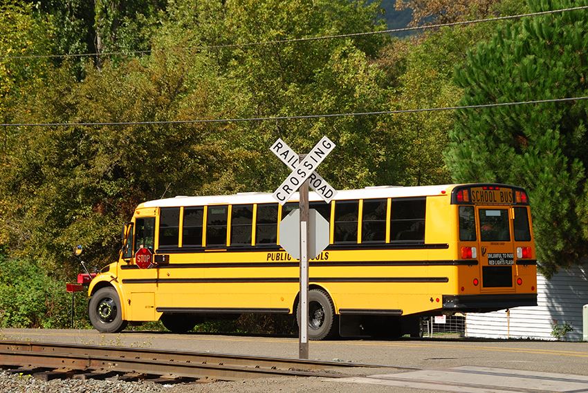 yellow school bus driving over railroad tracks